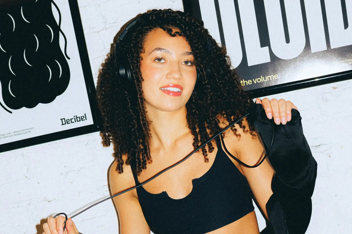Lachende vrouw met donkere krullen en een koptelefoon om haar nek voor Decibel posters