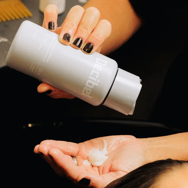 Thickening Conditioner wordt uit de flacon in een handpalm geknepen