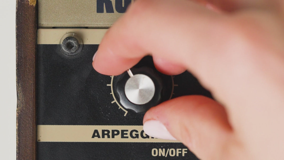 Hand draait aan de volumeknop van een versterker